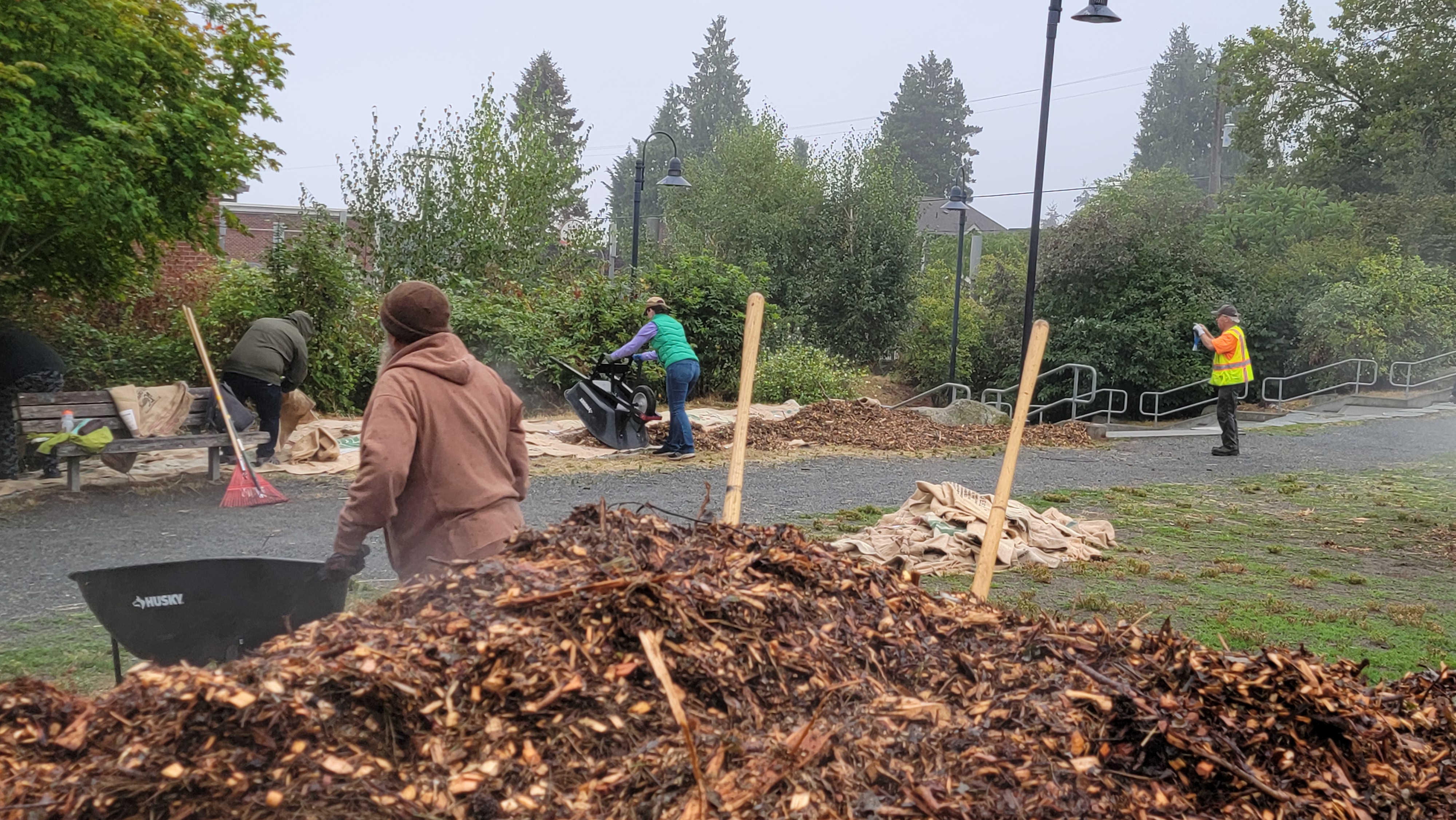 Several people move large piles of mulch.
