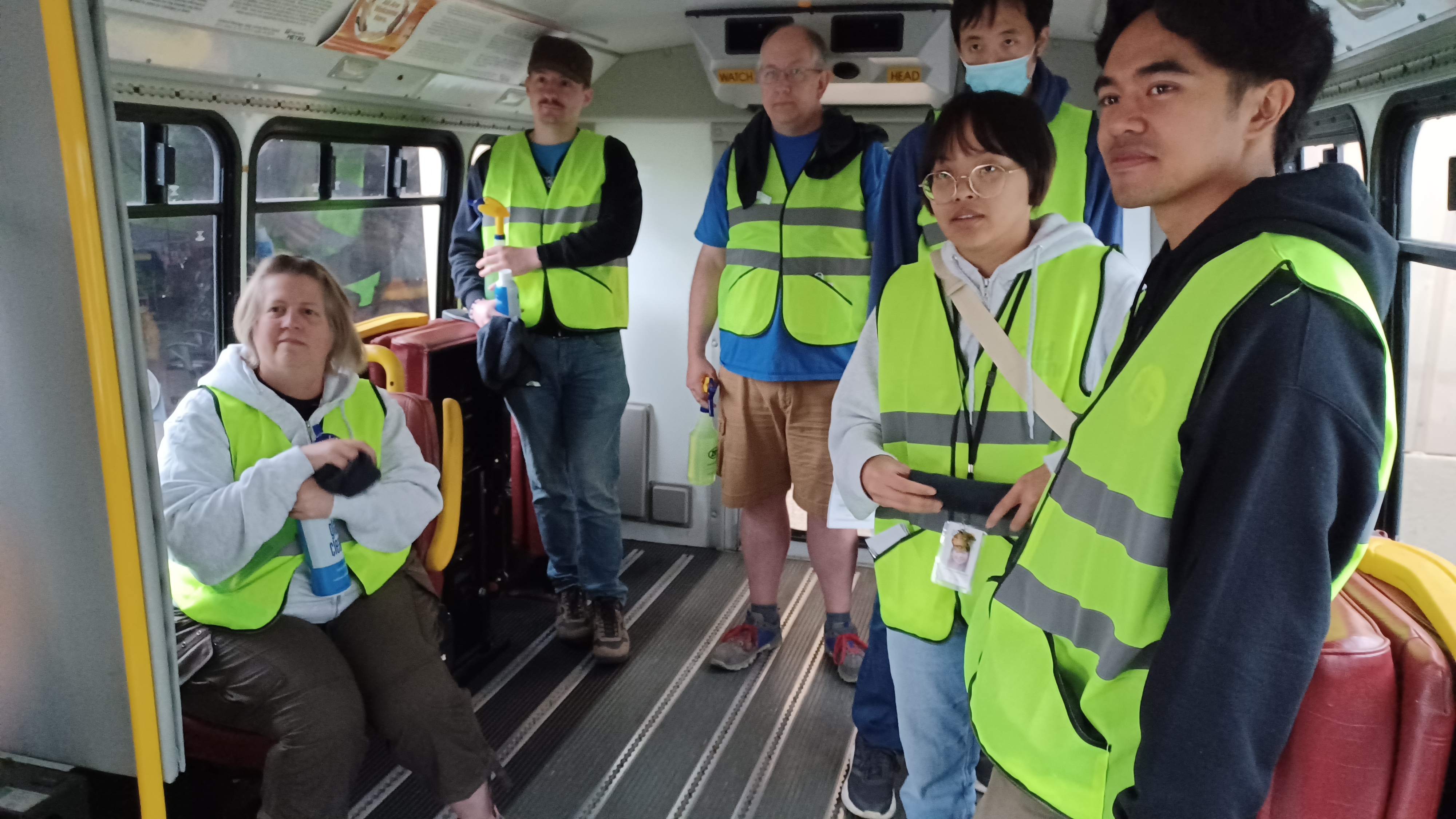 A group of people in yellow neon vests inside a paratransit bus.