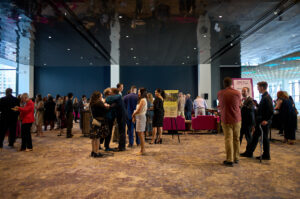 Guests mill about in a sleek convention center lobby filled with natural light.
