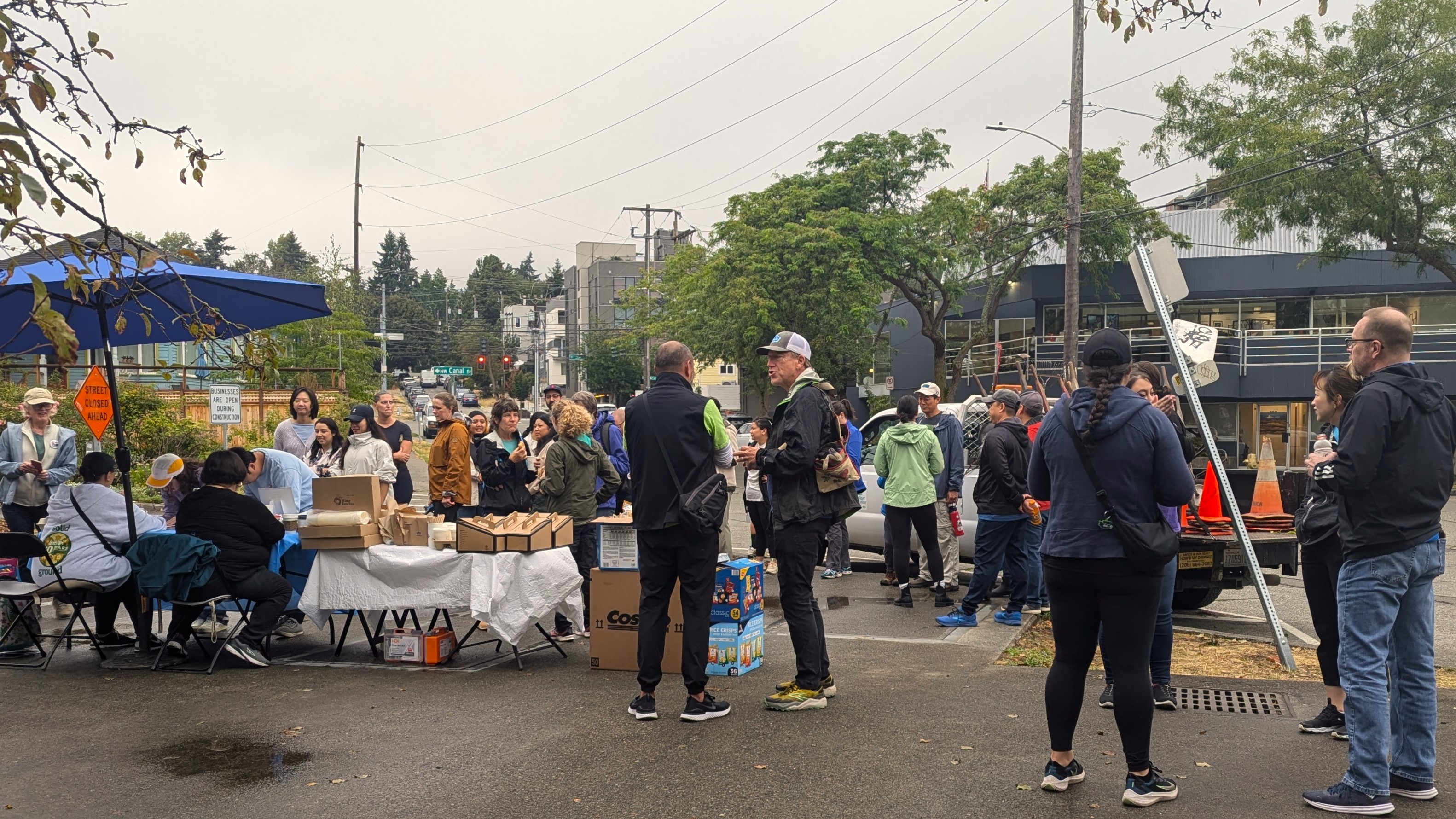A group of people mill about and chat in a parking lot.