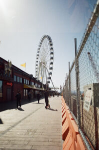 Photo of people riding scooters toward a giant Ferris wheel.