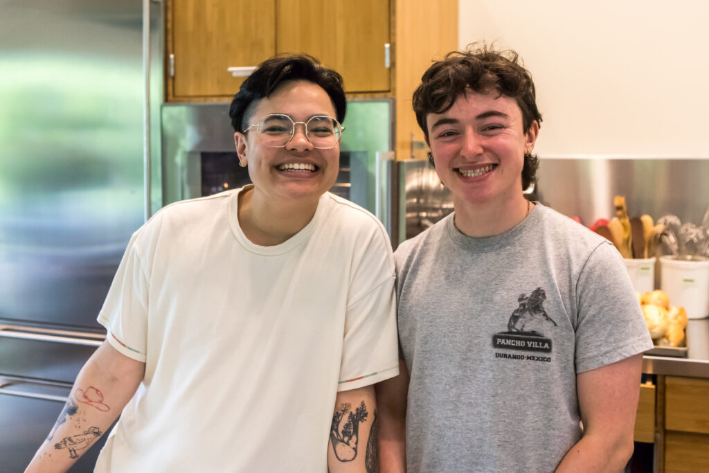 Two cooking class instructors smile as they pose together.