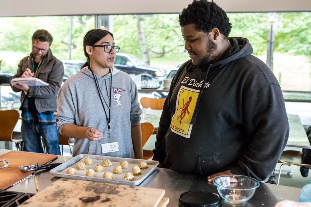 Two cooking class students chat about the cookies they're making.
