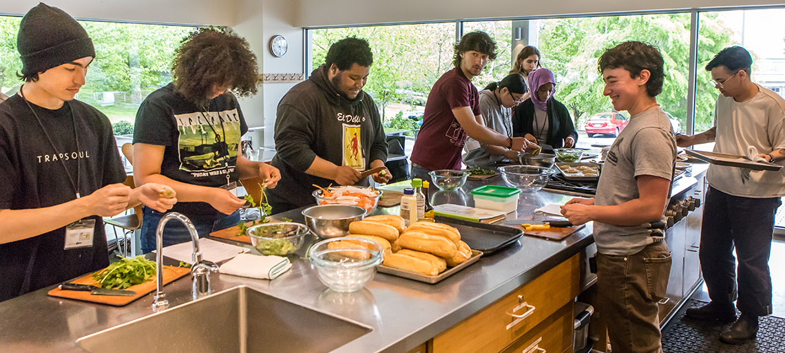Cooking class instructors and students make banh mi sandwiches together.