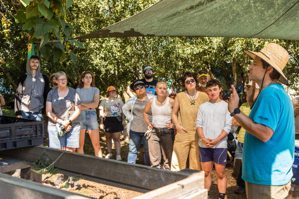 Several people stand around listening to a speaker.