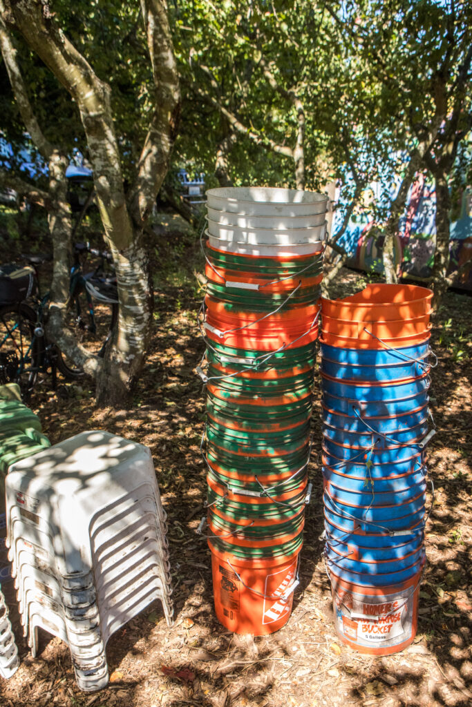 Two enormous stacks of orange, blue, green, and white 5-gallon buckets.