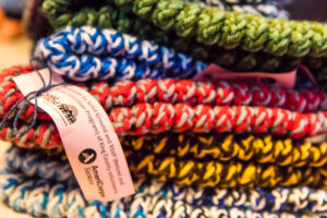 A stack of colorful knitted items with a pink tag tied to one hat.