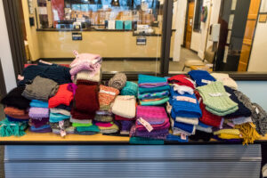 Knitted scarves stacked on a table.